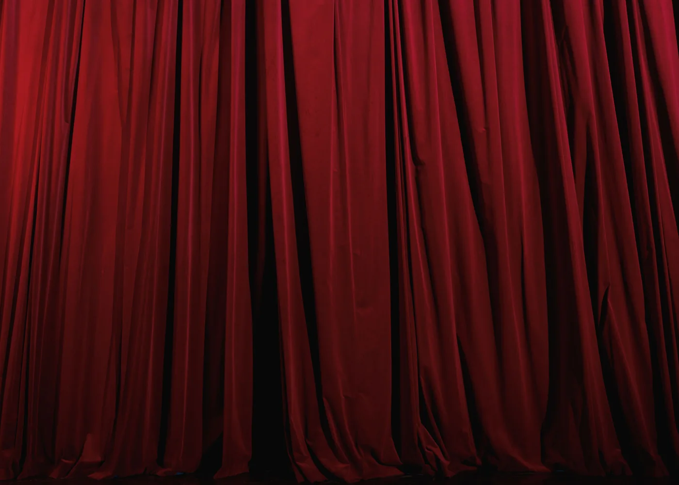 Un rico telón de teatro rojo plisado, iluminado en primer plano y con dramatismo (fotografía representativa del telón de un teatro-restaurante, no de la sala de Maison Milano)